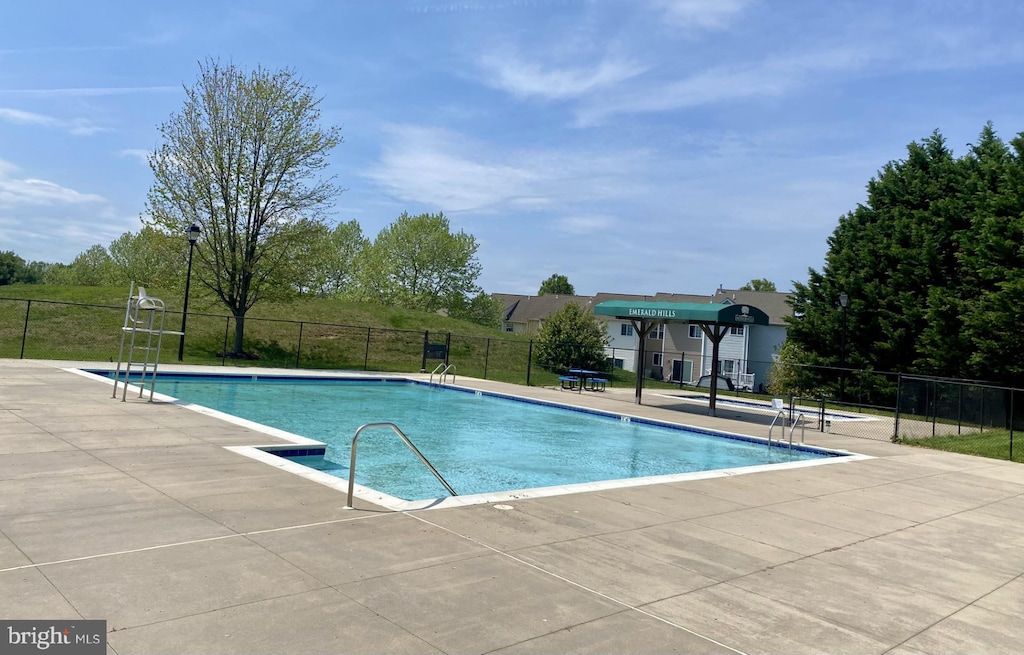 community pool with a patio and fence