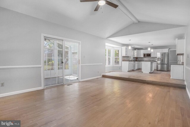 unfurnished living room with light wood-style floors, baseboards, lofted ceiling with beams, and a ceiling fan