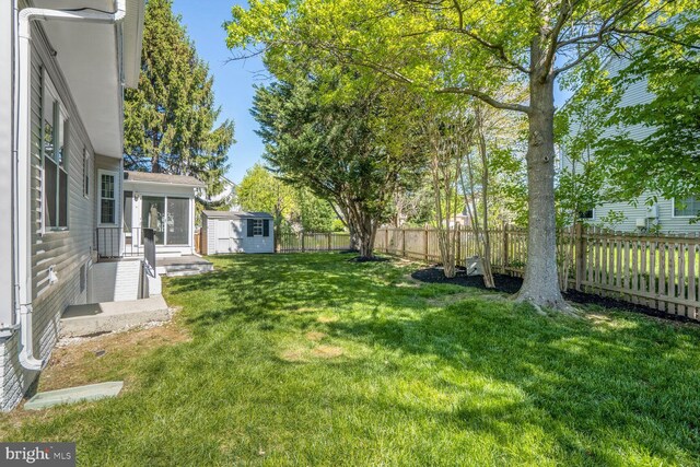 view of yard with an outdoor structure, a fenced backyard, and a shed