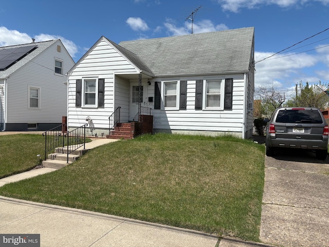 view of front facade with a front yard and roof with shingles