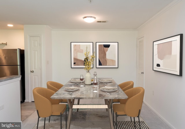 carpeted dining space with crown molding, baseboards, and visible vents
