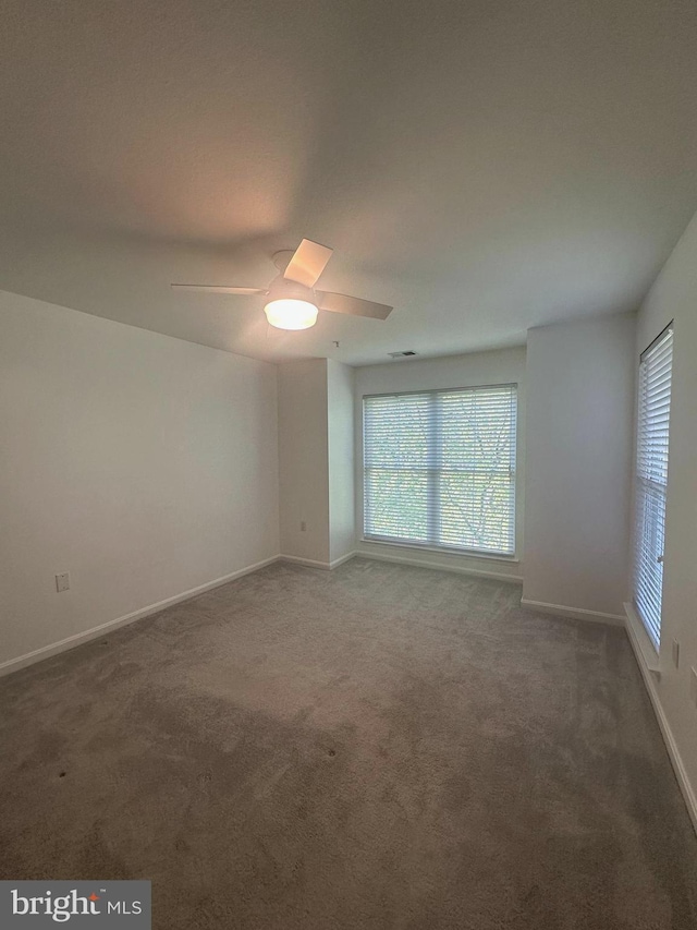 carpeted empty room featuring baseboards, plenty of natural light, and ceiling fan