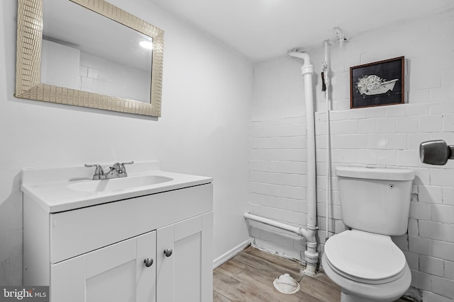 bathroom with toilet, wood finished floors, and vanity
