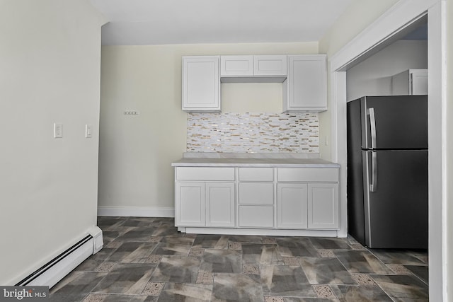 kitchen featuring freestanding refrigerator, baseboard heating, light countertops, white cabinetry, and tasteful backsplash
