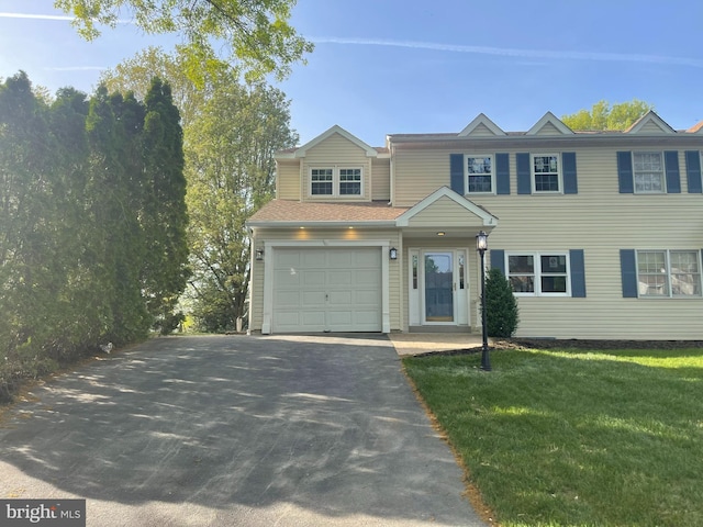 view of front of house featuring an attached garage, a front lawn, and aphalt driveway