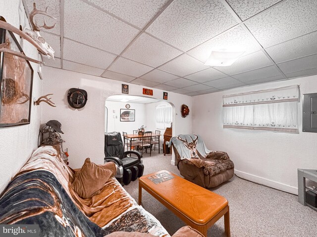 living room featuring electric panel, carpet, baseboards, arched walkways, and a drop ceiling