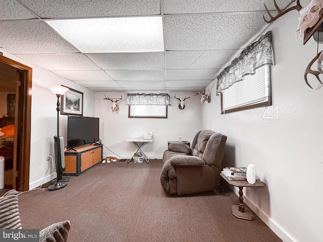 carpeted living area with a paneled ceiling and baseboards
