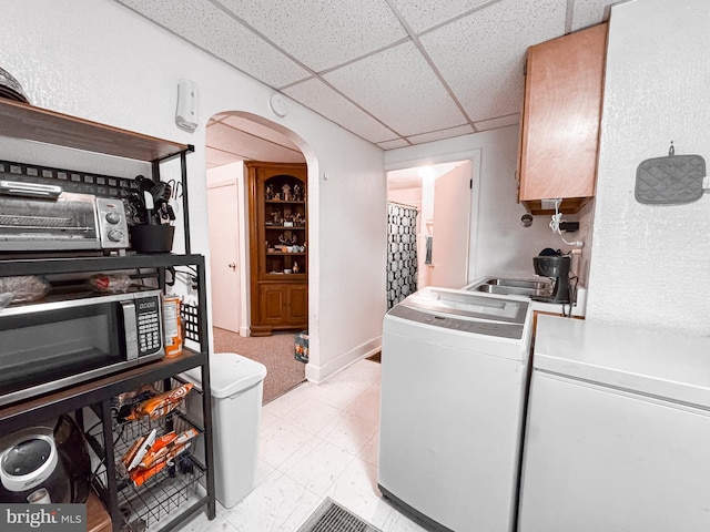 clothes washing area featuring washing machine and clothes dryer, arched walkways, a toaster, light floors, and laundry area