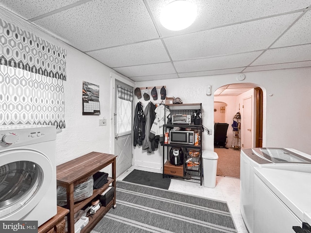 washroom with a textured wall, arched walkways, separate washer and dryer, light carpet, and laundry area