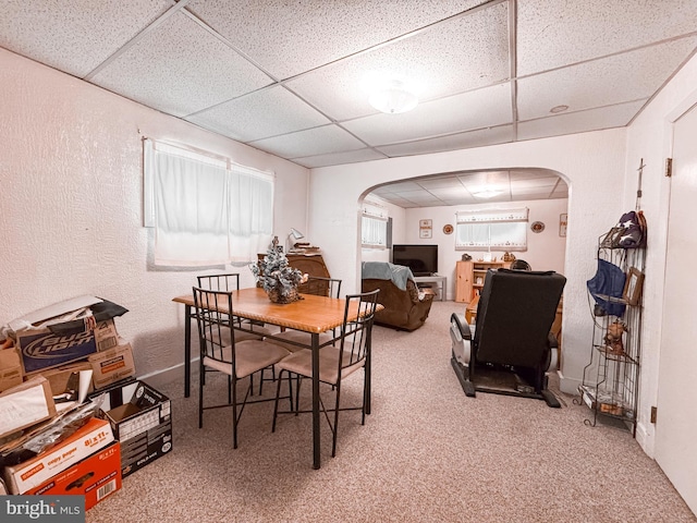 dining room with carpet, a paneled ceiling, and arched walkways