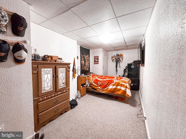 bedroom featuring a textured wall, a paneled ceiling, and carpet floors