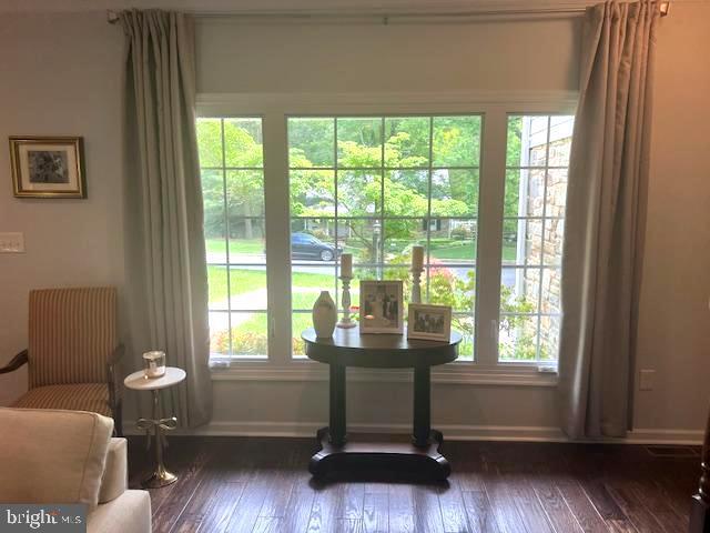 living area featuring plenty of natural light, dark wood-style floors, and baseboards