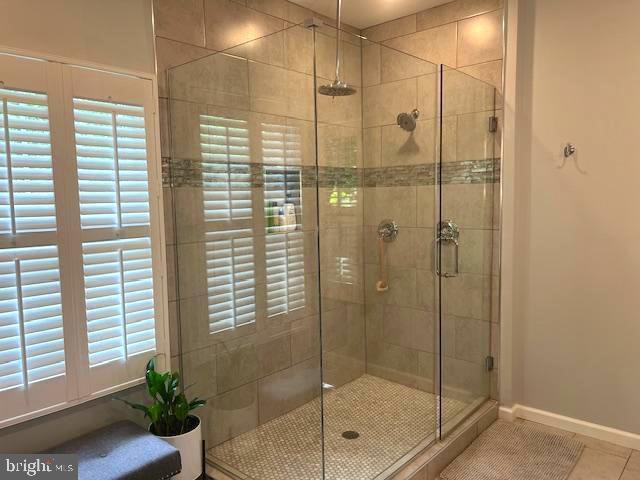 full bath featuring a stall shower, tile patterned flooring, and baseboards
