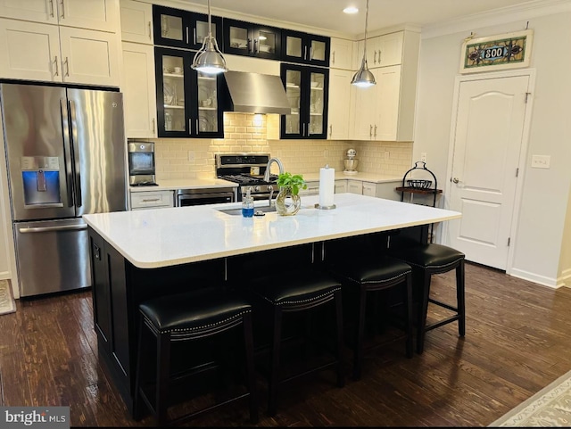 kitchen with stainless steel appliances, wall chimney exhaust hood, light countertops, baseboards, and dark wood finished floors