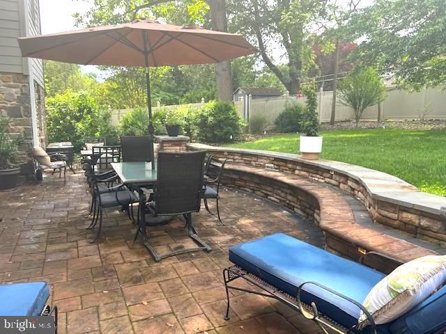 view of patio featuring outdoor dining area, an outbuilding, and a shed