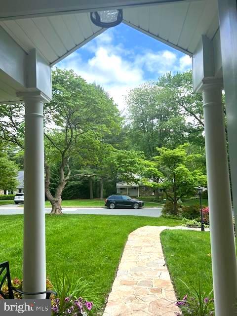 view of grassy yard with covered porch and view of wooded area
