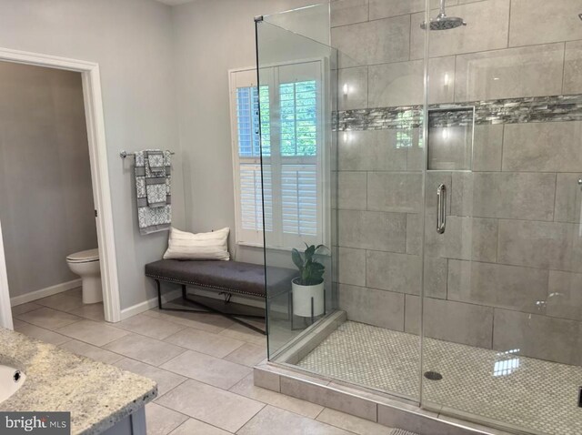 full bath with a shower stall, toilet, tile patterned floors, baseboards, and vanity