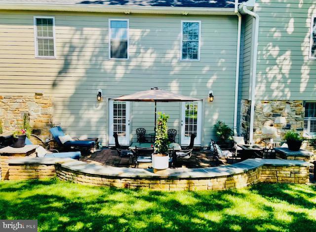 rear view of property with a patio, stone siding, and a yard