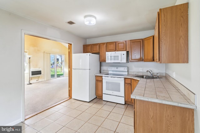 kitchen with brown cabinetry, white appliances, light tile patterned flooring, visible vents, and a sink