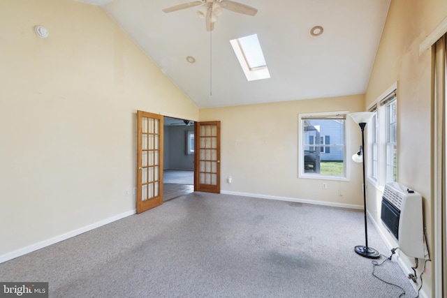 carpeted empty room featuring a skylight, french doors, high vaulted ceiling, a ceiling fan, and baseboards