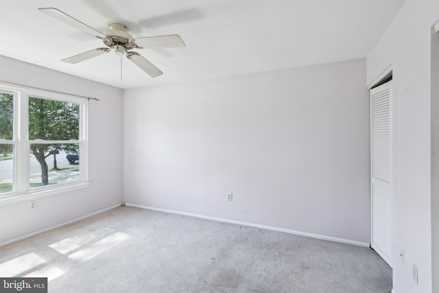 carpeted spare room featuring ceiling fan and baseboards