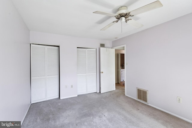 unfurnished bedroom featuring carpet flooring, two closets, visible vents, and baseboards