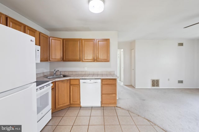 kitchen featuring a sink, white appliances, visible vents, light carpet, and tile counters