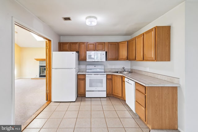 kitchen featuring visible vents, brown cabinets, a sink, and white appliances