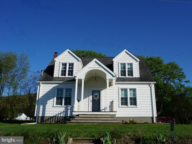 view of front of house with a shingled roof, a chimney, and a front yard