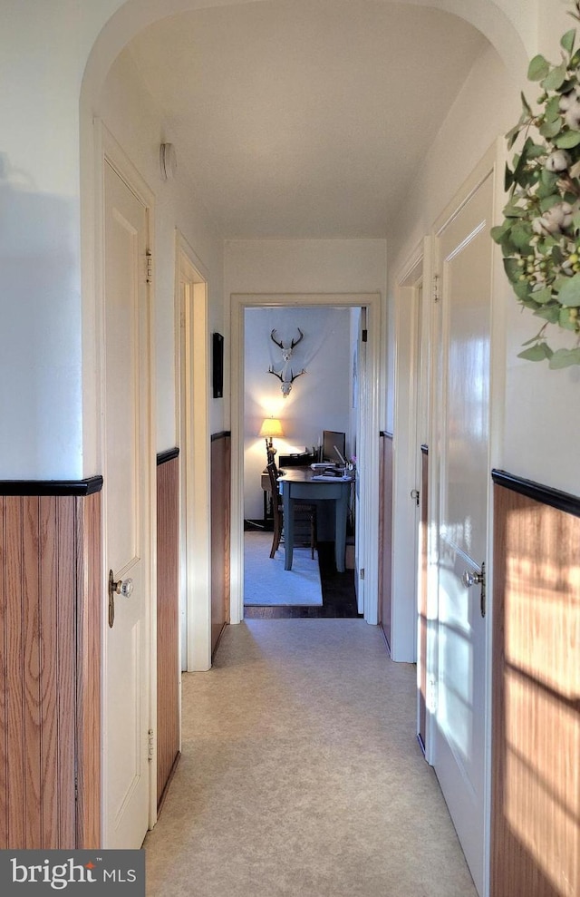 corridor with arched walkways and light colored carpet