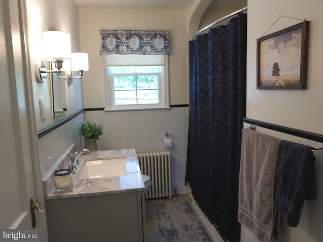 full bath featuring vanity, radiator, curtained shower, and wainscoting