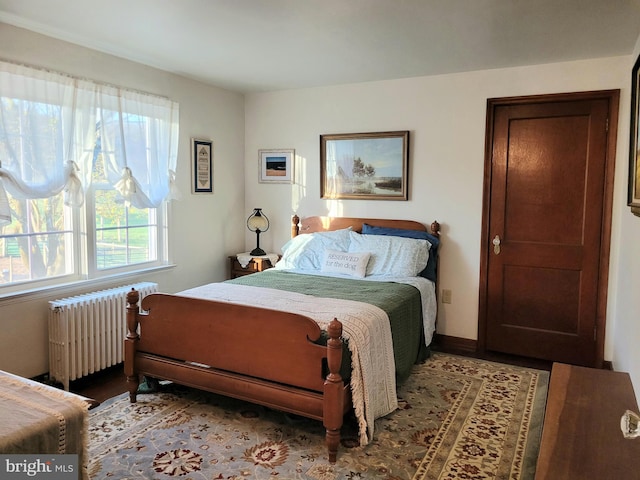 bedroom with radiator heating unit and wood finished floors