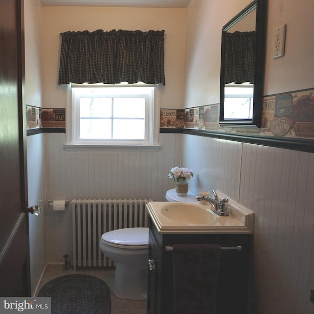 half bath with vanity, radiator, wainscoting, and toilet