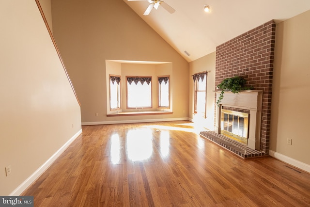 unfurnished living room with a fireplace, high vaulted ceiling, a ceiling fan, baseboards, and wood finished floors