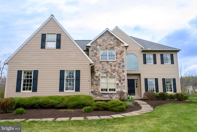 view of front of home featuring a front lawn and stone siding