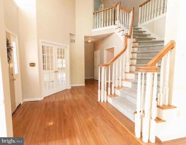entrance foyer with stairway, hardwood / wood-style floors, baseboards, visible vents, and french doors