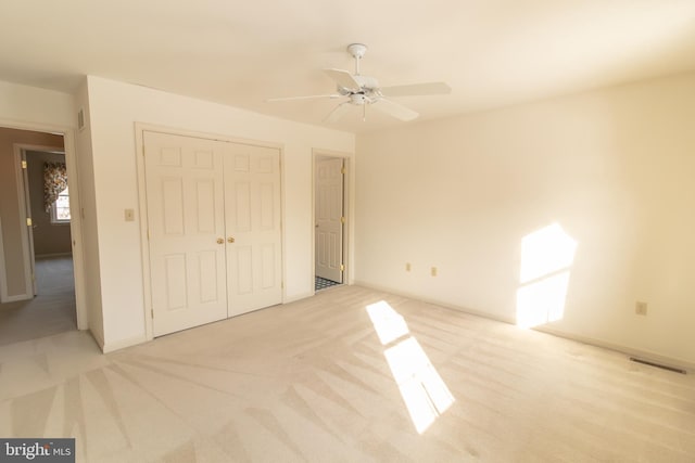 unfurnished bedroom with visible vents, a closet, a ceiling fan, and light carpet