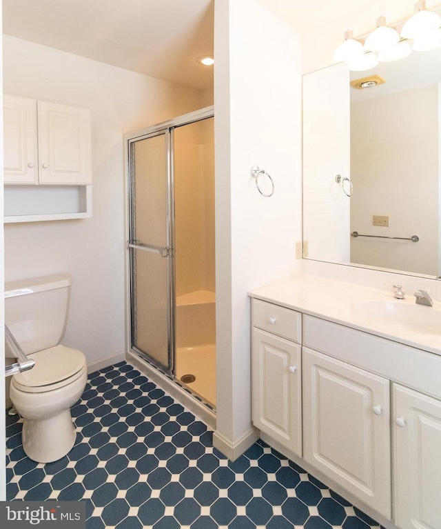 bathroom featuring baseboards, a shower stall, toilet, and vanity