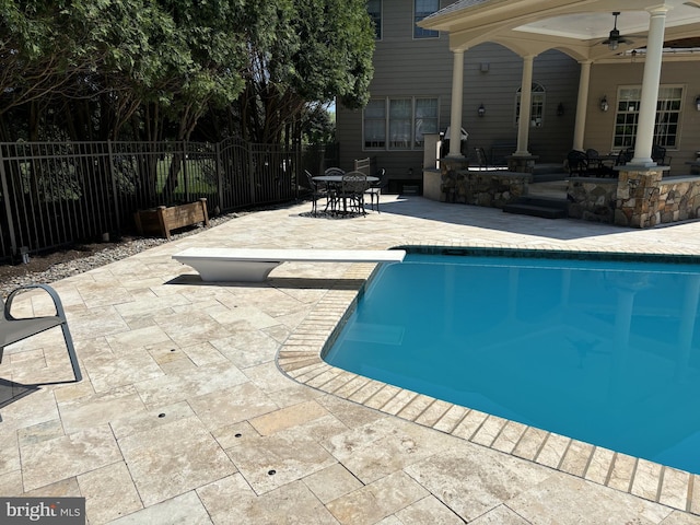 view of swimming pool with a diving board, fence, a fenced in pool, a patio area, and outdoor dining space
