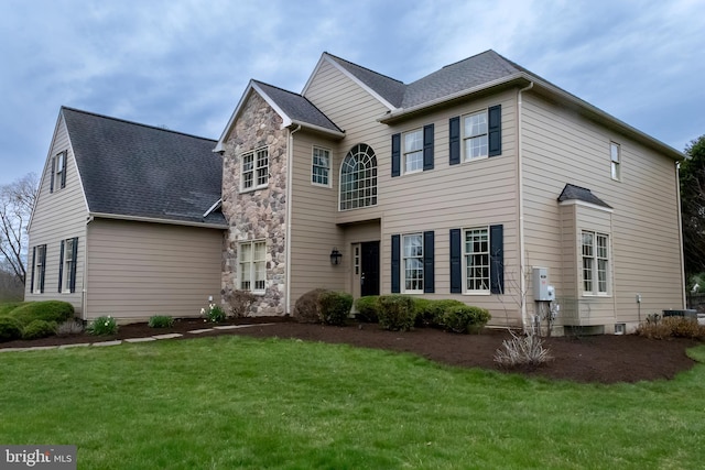 traditional-style house with central AC unit, a front yard, and stone siding