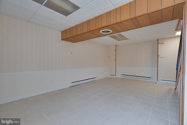 empty room featuring visible vents, wallpapered walls, wainscoting, and a baseboard radiator