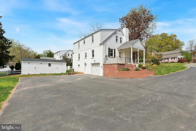 view of property exterior featuring a chimney, aphalt driveway, and an attached garage