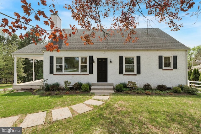 view of front of house with stucco siding, a chimney, a front yard, and a shingled roof