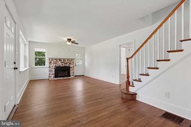 unfurnished living room with dark wood finished floors, visible vents, a ceiling fan, and stairway