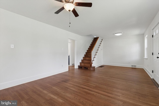 unfurnished living room featuring stairway, ceiling fan, visible vents, baseboards, and wood finished floors