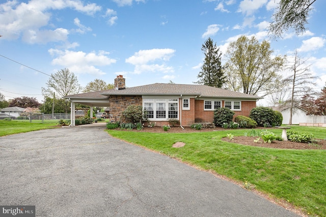 ranch-style house with a front lawn, fence, driveway, and brick siding