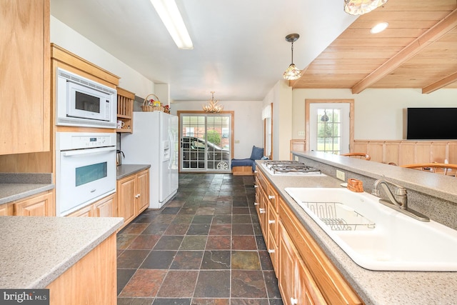 kitchen featuring plenty of natural light, a sink, stone tile flooring, and white appliances
