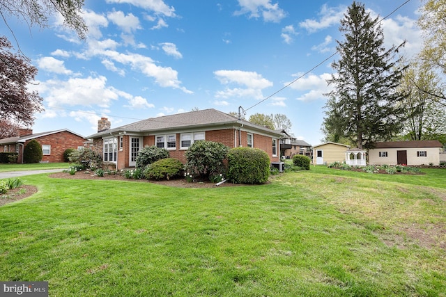 view of front of property with a chimney, brick siding, and a front yard