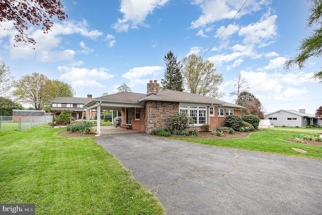 ranch-style home with a chimney, fence, aphalt driveway, a carport, and a front lawn