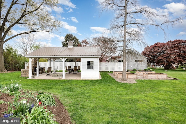 rear view of house featuring a patio, a chimney, a gazebo, a lawn, and a vegetable garden